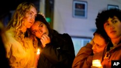 La gente permanece después de una vigilia por las víctimas de los tiroteos masivos del miércoles, el domingo 29 de octubre de 2023, frente a la Basílica de los Santos Pedro y Pablo en Lewiston, Maine. (Foto AP/Matt Rourke)