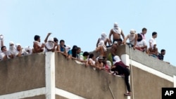 ARCHIVO - Presos permanecen en el techo de un centro de detención de la policía bolivariana en Caracas, Venezuela, en abril de 2015. 