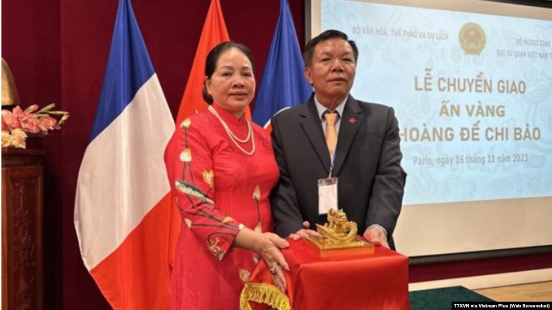 Chủ tịch Hội Cổ vật Bắc Ninh Nguyễn Thế Hồng (phải) đứng cạnh ấn vàng Hoàng đế chi bảo tại lễ chuyển giao cổ vật này tại Đại sứ quán Việt Nam ở Pháp, hôm 16/11. Ông Hồng mua chiến ấn triện vàng đúc từ thời vua Minh Mạng với giá 6,1 triệu euro.