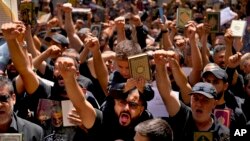 Hezbollah supporters chant slogans as they raise the Quran during a rally after Friday prayers in the southern Beirut suburb of Dahiyeh, Lebanon, July 21, 2023.