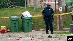 Afisa wa Polisi asimama katika eneo palipotokea shambulizi la Bunduki mjini Baltimore, Maryland.