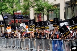 Writers and actors walk the picket line, July 14, 2023, at NBC Universal Studios in New York. The picketing came a day after the main actors’ union voted to join screenwriters in a double-barreled strike for the first time in more than six decades.