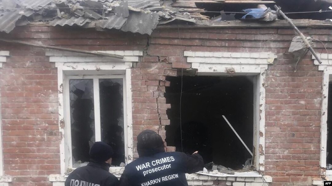 FILE - Petugas penegak hukum berdiri di samping sebuah rumah yang rusak akibat serangan rudal di Zolochiv, wilayah Kharkiv, 6 Februari 2024. (Handout / KANTOR KEJAKSAAN JENDERAL UKRAINA/AFP)