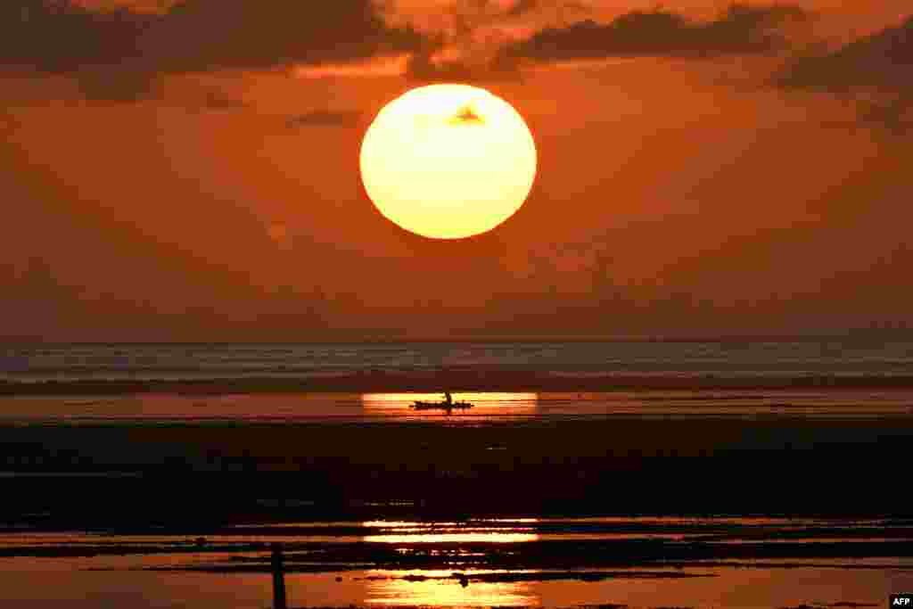 A fishing boat floats during sunrise at a beach in Sanur on the Indonesian resort island of Bali.