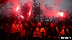 Demonstrators hold flares as Polish farmers protest over price pressures, taxes and green regulation, grievances shared by farmers across Europe, in Poznan, Poland, Feb. 9, 2024.