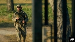 FILE - A National Guardsman walks along a border fence near the International Bridge where thousand of migrants, mostly from Haiti, have formed a makeshift camp, Sept. 20, 2021, in Del Rio, Texas.