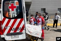 The Red Cross loads a patient, injured in a migrant detention center fire, into an ambulance, March 28, 2023, at a hospital in Cuidad Juarez, Mexico.