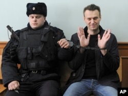 Russian opposition leader Alexey Navalny, right, poses for the press as he sits handcuffed in court in Moscow on March 30, 2017.
