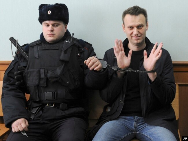 FILE - Russian opposition leader Alexei Navalny, right, poses for press as he sits handcuffed in court in Moscow, Russia on March 30, 2017. (AP Photo, File)