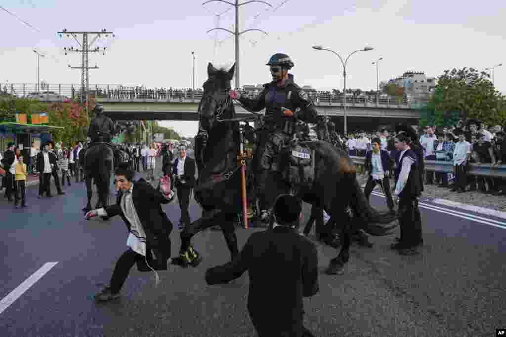 Polisi berkuda Israel membubarkan demonstran warga Yahudi Ultra-Ortodoks yang menghalangi jalan raya selama aksi protes terhadap kebijakan wajib militer Israel di Bnei Brak, dekat Tel Aviv. (AP)&nbsp;