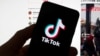 The TikTok logo is seen on a mobile phone in front of a computer screen which displays the TikTok home screen, March 18, 2023, in Boston. 