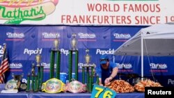 Seorang petugas menata panggung tempat perhelatan kontes makan hot dog tahunan yang digelar di Coney Island di Kota New York, pada 4 Juli 2023. (Foto: Reuters/Amr Alfiky)