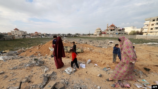 Palestinians inspect the destruction in Rafah on Feb. 18, 2024, following overnight Israeli air strikes on the southern Gaza Strip border city.