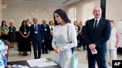 Presiden Azerbaijan Ilham Aliyev (kanan) dan istrinya sekaligus wakil presiden Azerbaijan, Mehriban Aliyeva, mengantre untuk mengambil kertas suara di sebuah tempat pemungutan suara di Baku, pada 1 September 2024. (Foto: Azerbaijani Presidential Press Office via AP)