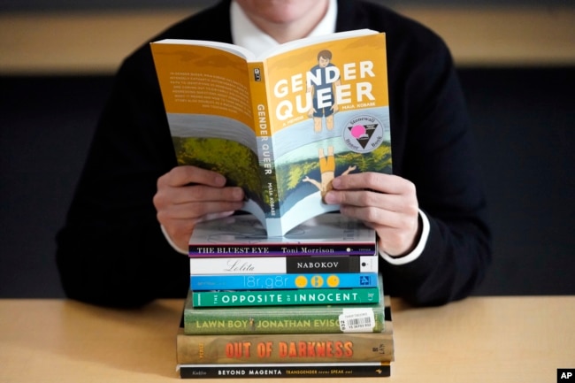 FILE - Amanda Darrow, director of youth, family and education programs at the Utah Pride Center, poses with books that have been the subject of complaints from parents on Dec. 16, 2021. (AP Photo/Rick Bowmer, File)