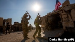 (FILE) Crewmen enter fighting vehicles at a US military in Syria.