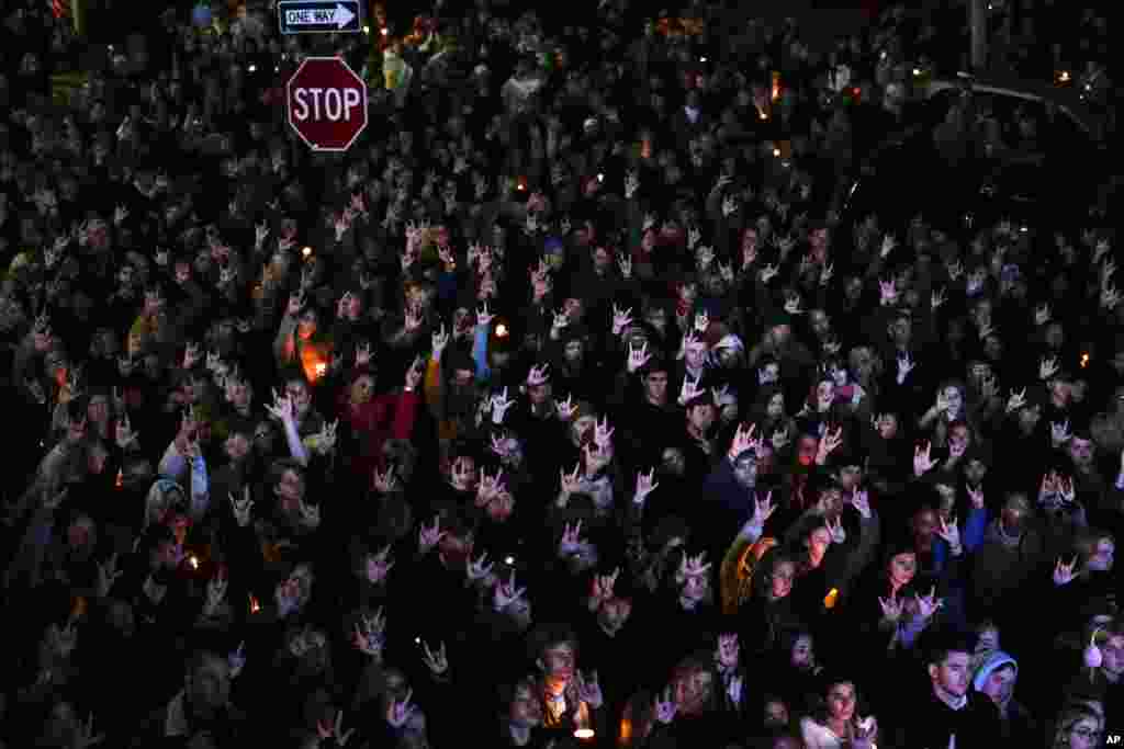 People sign &quot;I love you&quot; while gathered at a vigil for the victims of Wednesday&#39;s mass shootings, Oct. 29, 2023, outside the Basilica of Saints Peter and Paul in Lewiston, Maine.(AP Photo/Matt Rourke)