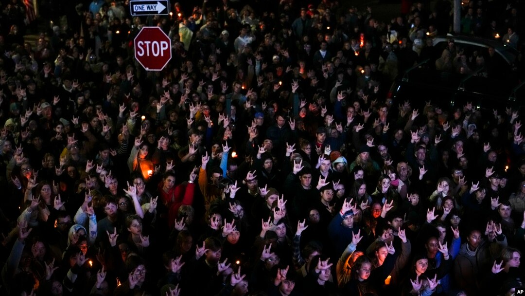 People sign "I love you" while gathered at a vigil for the victims of Wednesday's mass shootings, Oct. 29, 2023, outside the Basilica of Saints Peter and Paul in Lewiston, Maine.