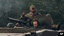 FILE - A Ukrainian soldier shows a V-sign atop a vehicle in Izium, Kharkiv region, Ukraine, Sept. 13, 2022. 