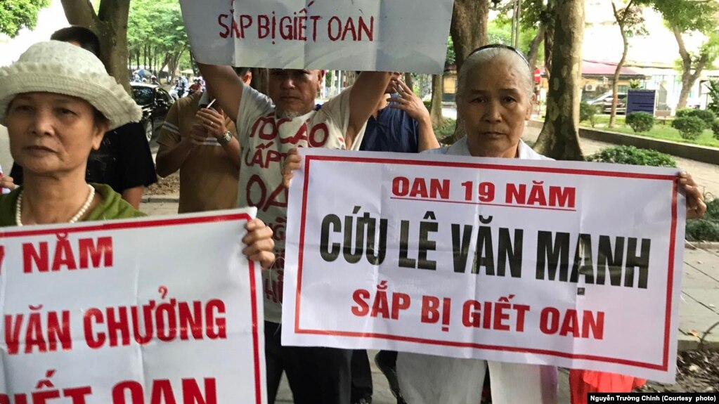 Bà Nguyễn Thị Việt (phải) giơ biểu ngữ kêu oan cho con trai Lê Văn Mạnh, người bị kết án tử hình vì tội "giết người" và "hiếp dâm" vào năm 2015, ở Hà Nội hôm 21/9.