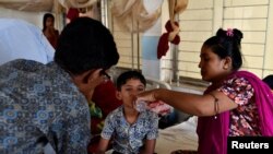 Seorang ibu memberikan minuman untuk anaknya yang terinfeksi demam berdarah saat dirawat di Mugda Medical College and Hospital di Dhaka, Bangladesh, 12 Oktober 2023. (REUTERS/Fatima Tuj Johora)