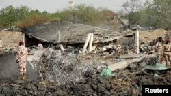 Army officers stand around blast damages after last night's fire that caused blasts at a military ammunition depot in N'Djamena, Chad, June 19, 2024. 