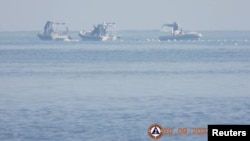 Chinese Coast Guard boats close to the floating barrier are pictured on Sept. 20, 2023, near the Scarborough Shoal in the South China Sea, in this handout image released by the Philippine Coast Guard on Sept. 24, 2023. (Handout via Reuters)
