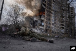 FILE - A Ukrainian police officer takes cover in front of a burning building that was hit in a Russian airstrike in Avdiivka, Ukraine, March 17, 2023.