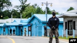 FILE - South Korean soldier, right, and United Nations Command soldier (background, in green) stand guard near the military demarcation line separating North and South, at the Joint Security Area of DMZ in the truce village of Panmunjom, Oct. 4, 2022.