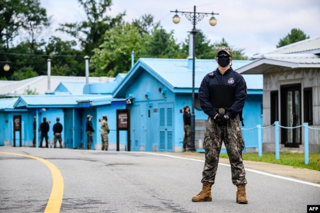 FILE - South Korean soldier (R) and United Nations Command soldier (background, in green) stand guard near the military demarcation line separating North and South, at the Joint Security Area of DMZ in the truce village of Panmunjom, Oct. 4, 2022.