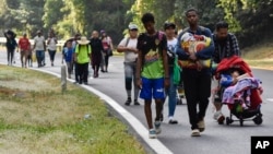 FILE — Migrants walk through Villa Comaltitlan, Chiapas state, southern Mexico, Dec. 27, 2023, heading toward the U.S. border. In a letter to President Joe Biden and congressional leaders, some state leaders say they are unable to cope with the volume of immigrants.