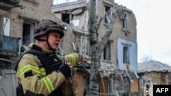 This handout picture taken and released by Ukrainian Emergency Service on Feb. 2, 2024, shows a rescuer outside a building damaged as a result of Russian air strike to the center of Kherson.