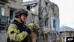 Slika koja je snimila i objavila ukrajinska hitna služba 2. februara 2024. prikazuje spasioca ispred zgrade oštećene kao rezultat ruskog zračnog napada na centar ukrajinskog grada Hersona.