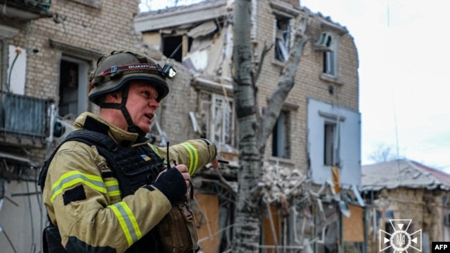 This handout picture taken and released by Ukrainian Emergency Service on Feb. 2, 2024, shows a rescuer outside a building damaged as a result of Russian air strike to the center of Kherson.