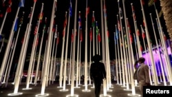 Los delegados se encuentran cerca de los mástiles de banderas en la Expo City de Dubái después de asistir a la Cumbre Mundial de Acción Climática, durante la Conferencia de la ONU sobre el Cambio Climático en Dubái, Emiratos Árabes Unidos, el 1 de diciembre de 2023.