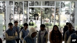 Photographs of people who disappeared during Argentina's dictatorship are displayed on the wall where students walk through the ESMA Museum and Site of Memory on Sept. 19, 2023. (AP Photo/Rodrigo Abd)