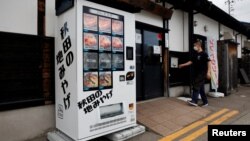 Menu mesin penjual otomatis menawarkan daging Beruang Hitam Asia, Daging Sapi Akita, dan ikan sungai kering di depan restoran Mie Soba di Semboku, prefektur Akita, Jepang, 6 April 2023. (REUTERS/Irene Wang)