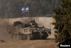 An Israeli soldier rides in an armored personnel carrier near the border with Gaza, after a temporary truce between Israel and the Palestinian Islamist group Hamas expired, in Israel, Dec. 1, 2023.