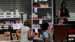 (FILE) People look at food prices in a private business in Havana.