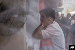 A man cools off during a heat wave under an open air shower in Baghdad, Iraq, July, 6, 2023.