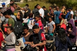 FILE - Migrants wait to be processed by U.S. Customs and Border Protection after they crossed the Rio Grande and entered the U.S. from Mexico, Oct. 19, 2023, in Eagle Pass, Texas.