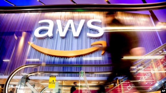 FILE - An attendee walks through AWS re:Invent 2022, a conference hosted by Amazon Web Services, in Las Vegas, Nov. 30, 2022. The job cuts announced March 20, 2023, will hit profitable areas for the company, including its cloud computing unit AWS.