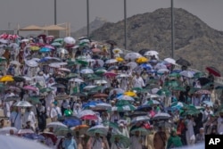 Muslim pilgrims use umbrellas to shield themselves from the sun as they arrive to cast stones at pillars in the symbolic stoning of the devil, the last rite of the annual hajj, in Mina, near the holy city of Mecca, Saudi Arabia, June 18, 2024.