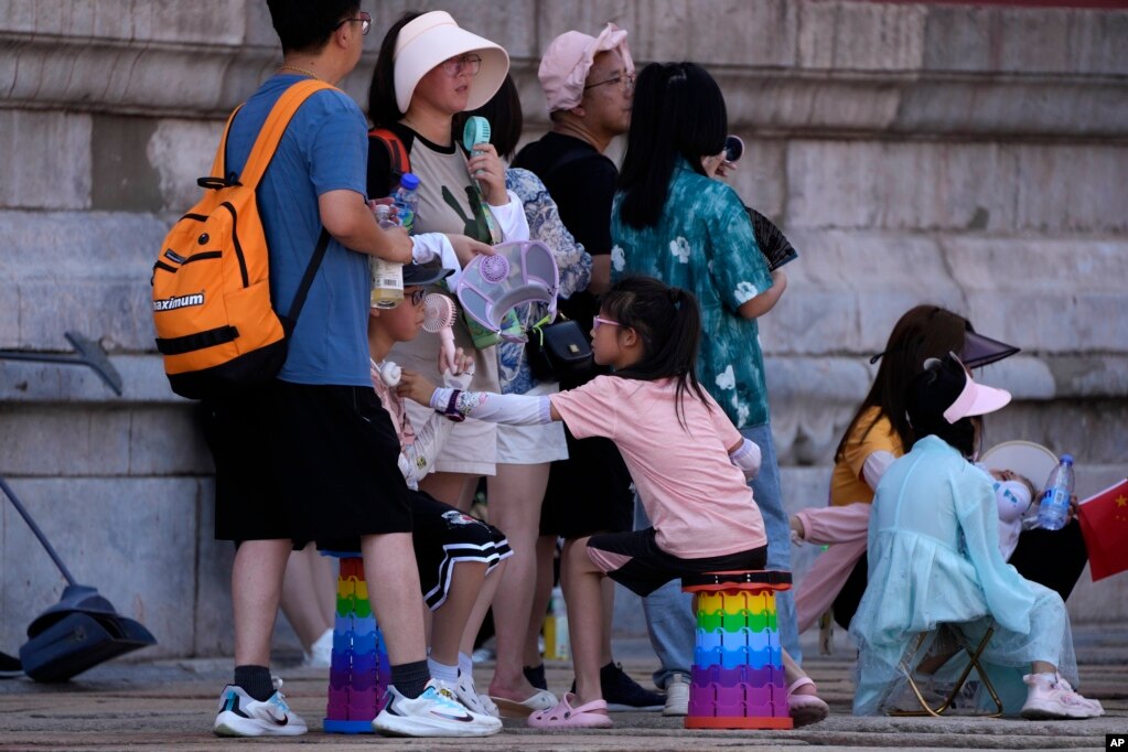 前来北京参观故宫的游客手持小电扇在阴凉地里排队等候入门。（2023年7月7日）(photo:VOA)