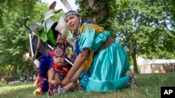 T'ata Begay, of the Choctaw/Taos Pueblo Nations in Oklahoma, prepares her son, Okhish Homma Begay, 2, who is of the Navajo and Chocktaw/Taos Pueblo Nations, ready for a performance at the Smithsonian Folklife Festival in Washington, June 26, 2024.