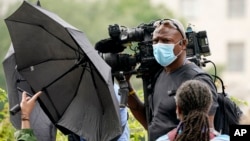 FILE - A news media cameraman is blocked with umbrellas by counter protesters at Freedom Plaza in Washington, Sept. 18, 2021, as they try to prevent coverage of a planned rally by supporters of former President Donald Trump.