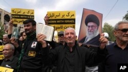 A protester holds up a copy of the Quran and a portrait of the Iranian Supreme Leader Ayatollah Ali Khamenei in a demonstration against Sweden in Tehran, July 21, 2023. Thousands of people took to the streets in a handful of Muslim-majority countries to express their outrage at the planned desecration of a copy of the Quran in Sweden.