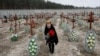 Una mujer, residente local, coloca flores en las tumbas de personas no identificadas asesinadas por soldados rusos durante la ocupación de la ciudad de Bucha, en las afueras de Kiev, Ucrania, el 24 de febrero de 2023.