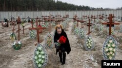 Una mujer, residente local, coloca flores en las tumbas de personas no identificadas asesinadas por soldados rusos durante la ocupación de la ciudad de Bucha, en las afueras de Kiev, Ucrania, el 24 de febrero de 2023.