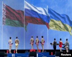 Tim Rusia (tengah), Belarus (kiri) dan Ukraina mendengarkan lagu kebangsaan Rusia pada Kejuaraan Senam Ritmik Eropa ke-31 di Minsk, Belarusia, 2 Mei 2015. Rusia memenangkan emas, perak Belarusia, dan perunggu Ukraina dalam kompetisi final beregu. (REUTERS/Vasily Fedosenko)